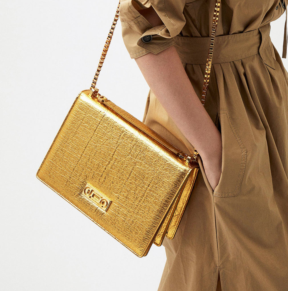 The Cristiana Vegan Shoulder Bag by Studio Tondini. Gold version worn by a model in a refined studio setting, highlighting the luminous 24K gold-plated chain and the sculptural day-to-evening elegance.