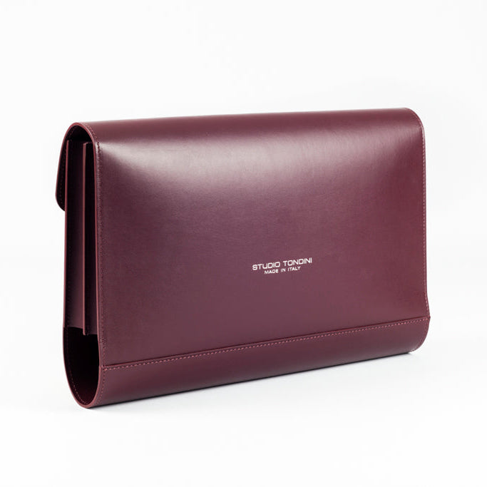 The Document Holder by Studio Tondini. Three-quarter view of burgundy leather bag, highlighting impeccable craftsmanship and dual-compartment structure.